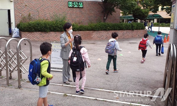 23일 서울의 한 초등학교에서 1학년 학생들이 거리를 두고 한 명씩 차례차례 교문을 들어서고 있다.