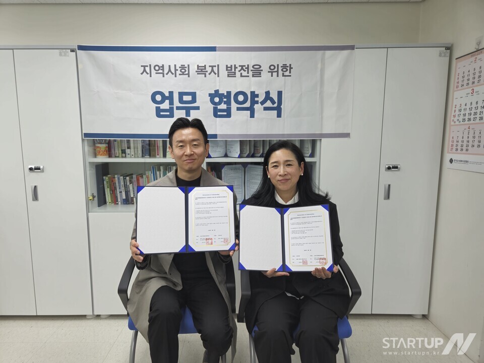 우리 카지노 김종수 대표(왼쪽)와 고양시지축종합사회복지관 송미령 관장이 업무협약 체결 후 협약서를 들고 기념촬영을 하고 있다