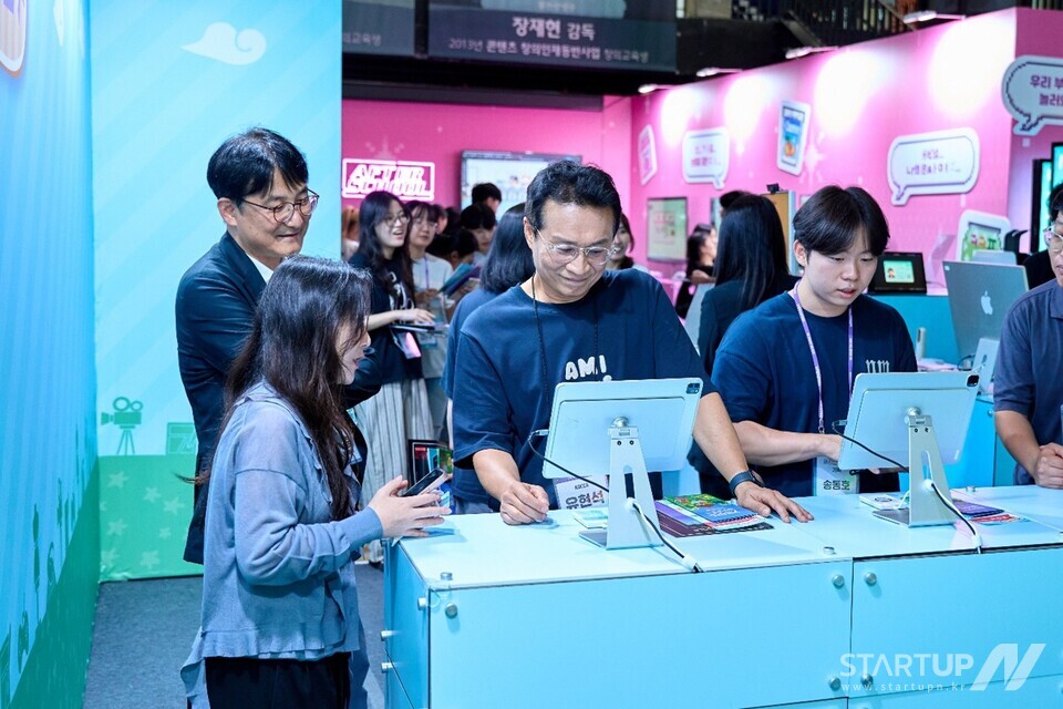 콘진원 유현석 원장직무대행(가운데)과 김일중 메이저카지노사이트기반본부 본부장(왼쪽)이 교육생에게 프로젝트에 대한 설명을 듣고 있다(제공=한국메이저카지노사이트진흥원)