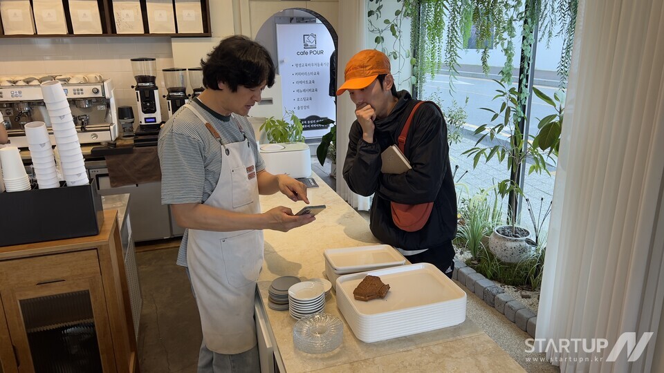 ブックメーカー野球ジュパンのデザインについて話し合う若いデザイナーとカフェのオーナー